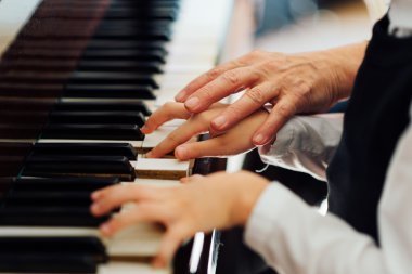 müzik öğretmeni öğrencinin doğru oynamak için yardımcı olur.