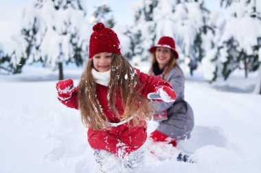 Anne ile kızı karla kaplı parkta oynamak 