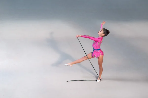 Mädchen im Kleid turnt mit Gymnastikseil — Stockfoto