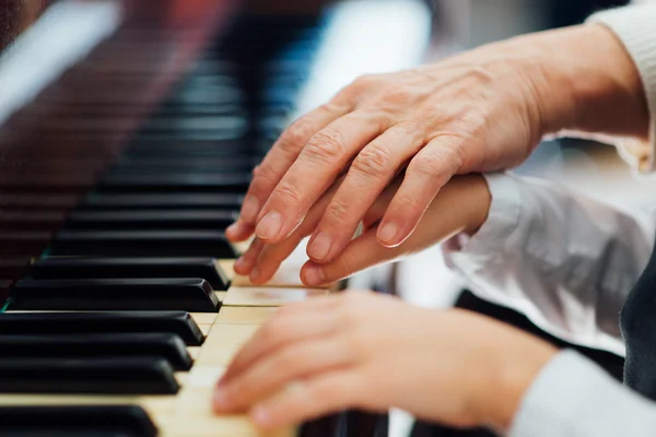 Mano de piano maestro experimentado ayuda al estudiante Imágenes de stock libres de derechos