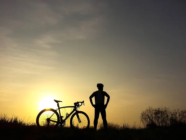 骑自行车的人站在小山上看着阳光和放松 — 图库照片