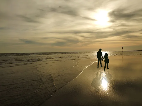 Vista de una joven pareja caminando a lo largo de la orilla durante el atardecer — Foto de Stock