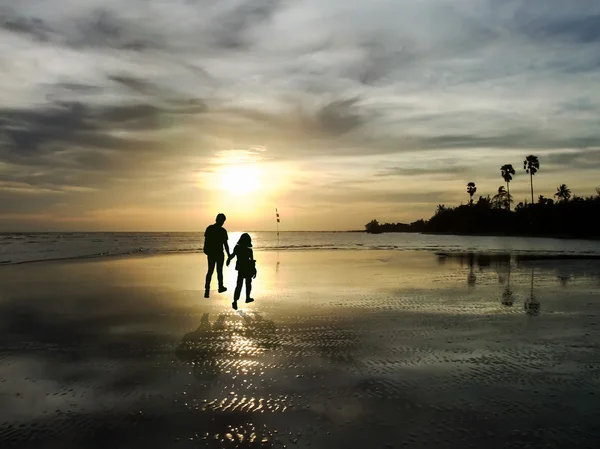 Vista do jovem casal caminhando ao longo da costa durante o pôr do sol — Fotografia de Stock