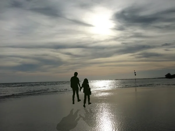 View of young couple walking along the shore during sunset — Stock Photo, Image