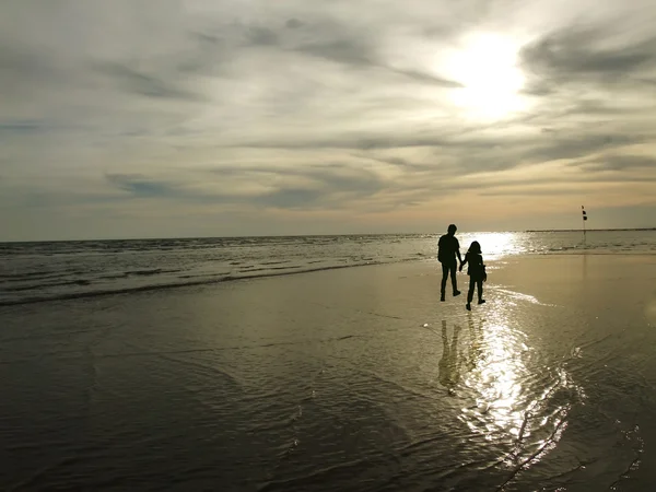 Vista de una joven pareja caminando a lo largo de la orilla durante el atardecer — Foto de Stock