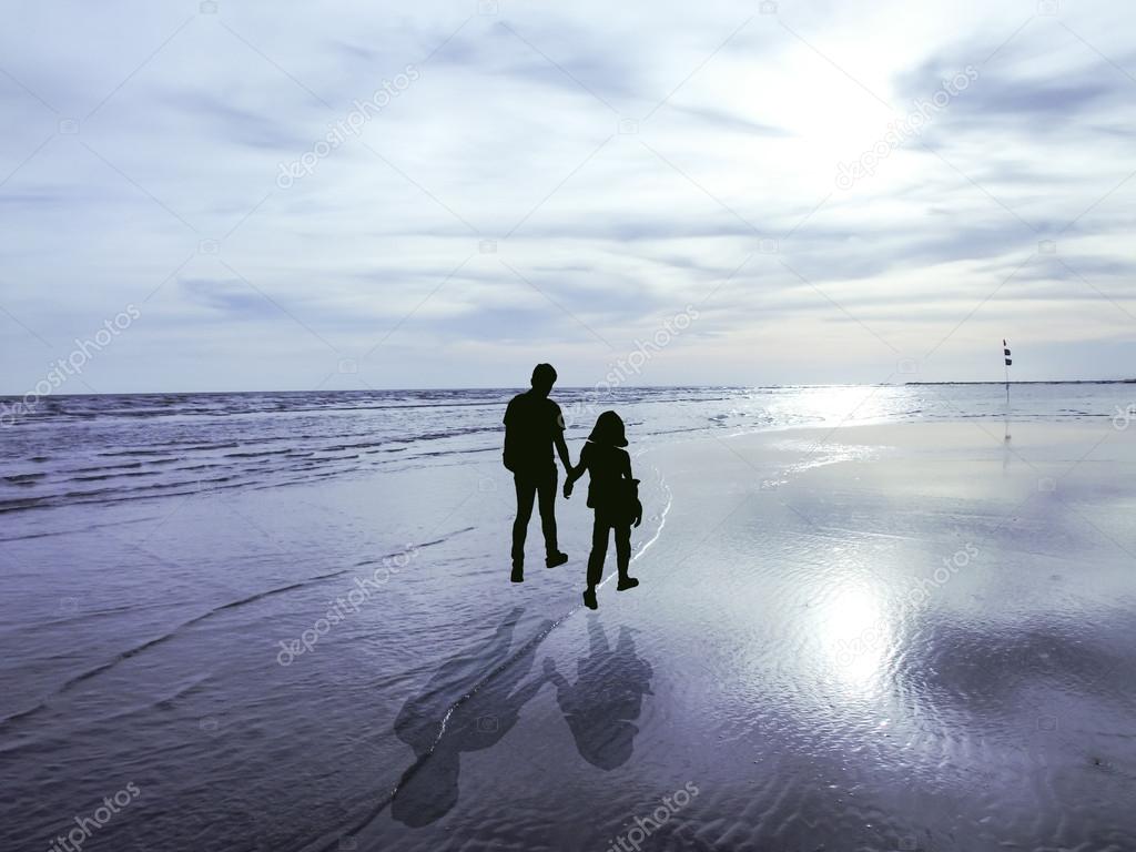 view of young couple walking along the shore during sunset