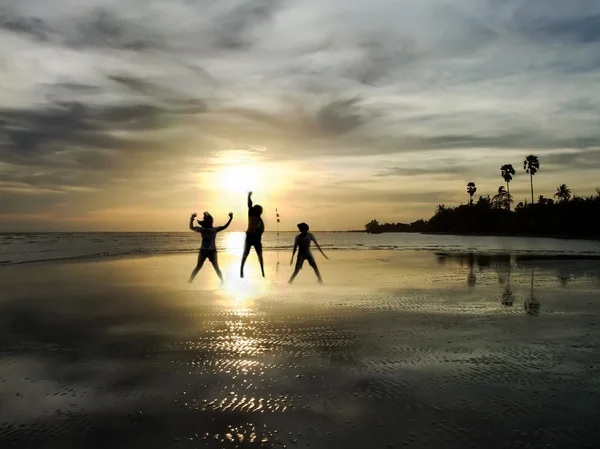 Young people jumping on the beach with sunset background — Stock Photo, Image