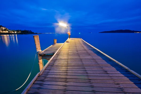 夕暮れ時に海で木製の橋. — ストック写真