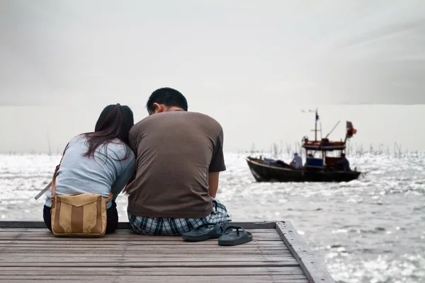 Пара під час заходу сонця сидить біля дерев'яного мосту на шляху до — стокове фото