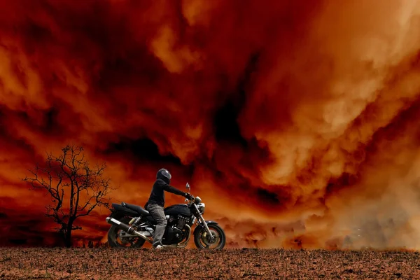 Motorkář stojící se svou motorkou v bouři — Stock fotografie