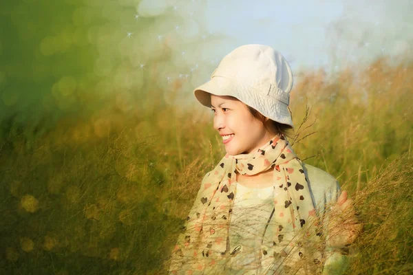 Young woman is standing in meadow with raised arms enjoying sunl — Stock Photo, Image