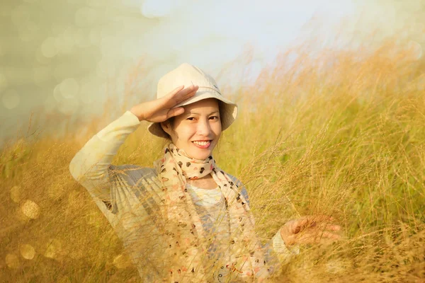 Mujer joven está de pie en el prado con los brazos levantados disfrutando del sol — Foto de Stock