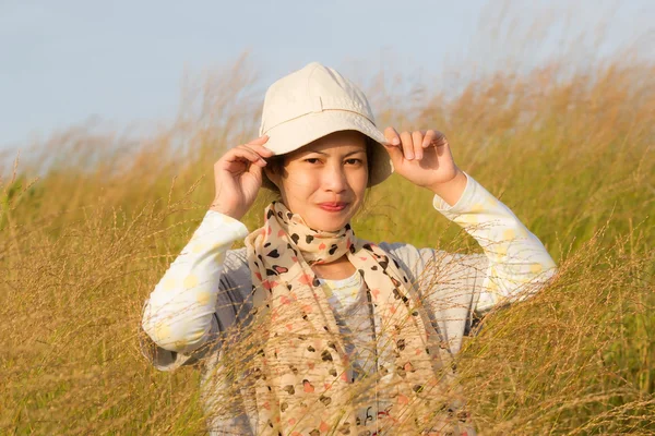 Young woman is standing in meadow with raised arms enjoying sunl — Stock Photo, Image