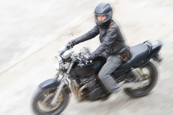 Motociclista em capacete e casaco preto andando na estrada . — Fotografia de Stock