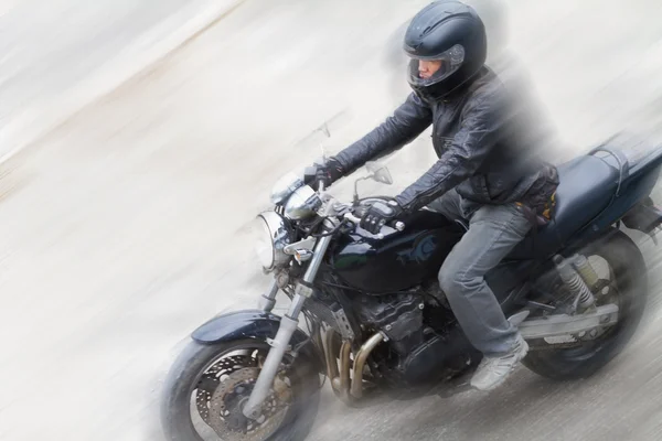Biker in helm en zwarte jas rijden op de weg. — Stockfoto