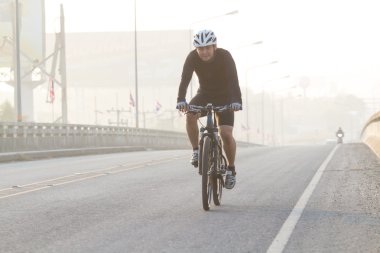 Men riding bicycles on the bridge haze. clipart