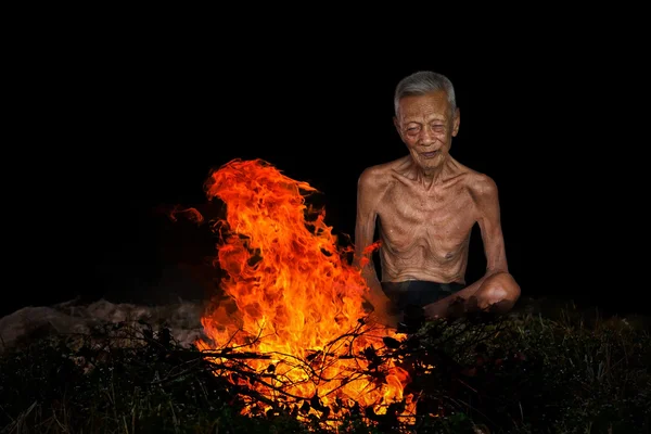 Old man sitting next to a fire — Stock Photo, Image