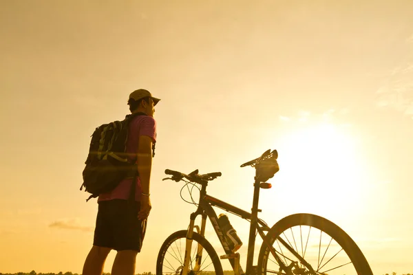 Stand uomo su Mountain bike silhouette in sunris — Foto Stock