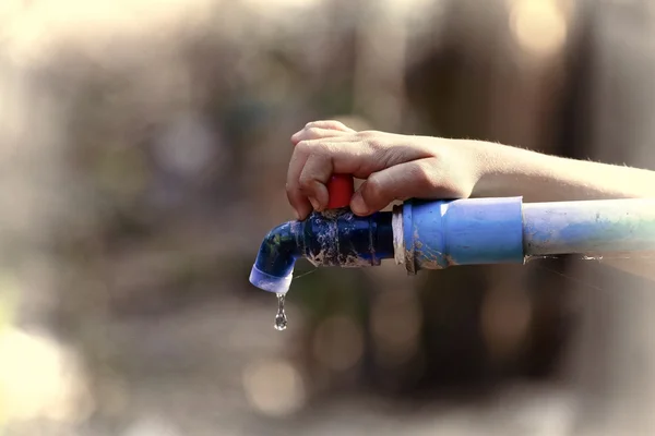 Hand houden buiten waterkraan met buis — Stockfoto