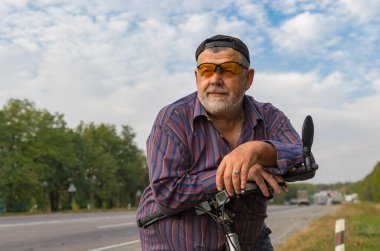 Beyaz sakallı son sınıf öğrencisinin bisiklet sürmeye hazırlandığı açık hava portresi.