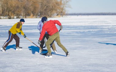 Dnipro, Ukrayna - 22 Ocak 2017: Ukrayna 'da Dnepr nehrinde amatör hokey oynarken sürü için savaşan üç olgun adam