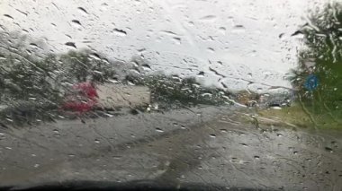 Yol kenarında duran eski bir arabayla rüzgar perdesinden yağmurlu bir yol.