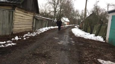 Bastonlu yaşlı Ukraynalı köylü kış mevsiminde köy sokağına çıkar.