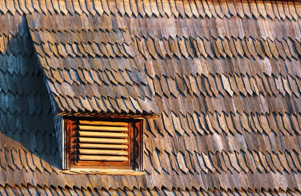 Pequena janela de sótão em grade no telhado de telha de madeira temperado velho — Fotografia de Stock