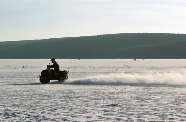 Motorista de moto Quad monta sobre lago congelado — Fotografia de Stock