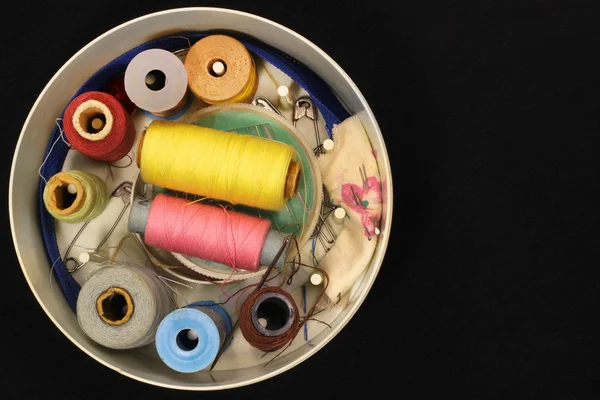 Oude ronde doos met klossen van wol, naalden en spelden op zwart — Stockfoto