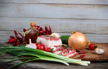 Sebze ve zeytinyağı doğrama kurulu üzerinde yağlı domuz pastırması