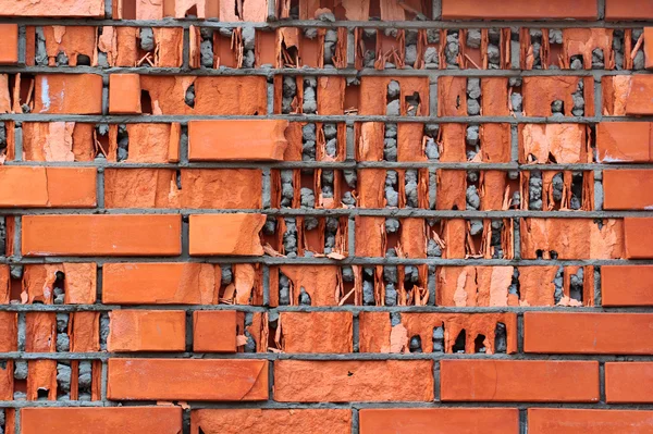 Baixa qualidade enfrentando tijolos. Parede de tijolo vermelho destruído por água congelada — Fotografia de Stock