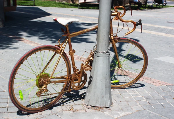 Golden painted bicycle chained to a street lamppost — Stock Photo, Image