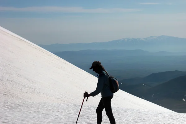 Siluett av kvinna trekker på snö berg slutta — Stockfoto