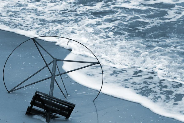 Vecchia struttura in metallo di ombrellone in riva al mare. Onde su una spiaggia di sabbia — Foto Stock