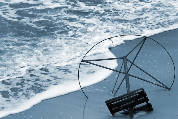 Gamla stomme av parasoll på en havsstrand. Vågor på en sandstrand — Stockfoto