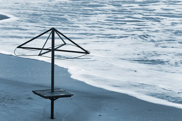 Stary stelaż parasola na brzegu morza. Fale na plaży piasek — Zdjęcie stockowe