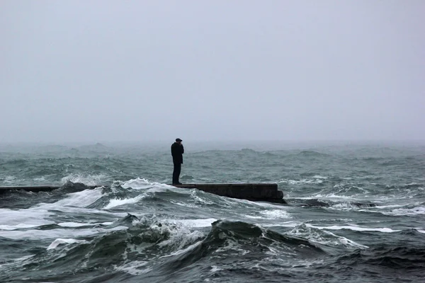 Man talar över telefonen stående på en pir under havet storm — Stockfoto