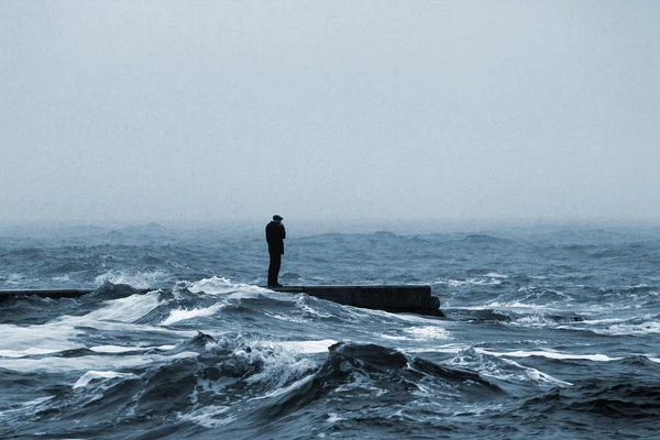 Mężczyzna, który mówi przez telefon stojący na molo podczas burzy morze — Zdjęcie stockowe