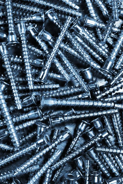 Many metal furniture screws - blue tinted background