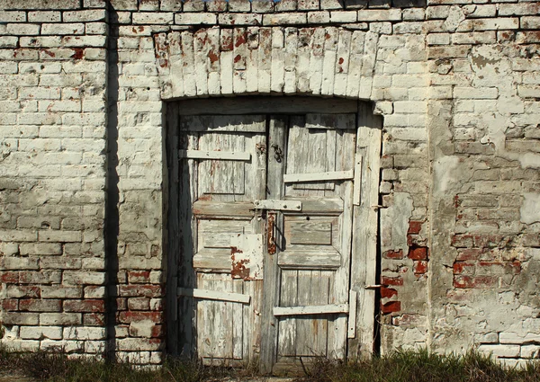 Старая выветрившаяся деревянная дверь в кирпичной стене — стоковое фото