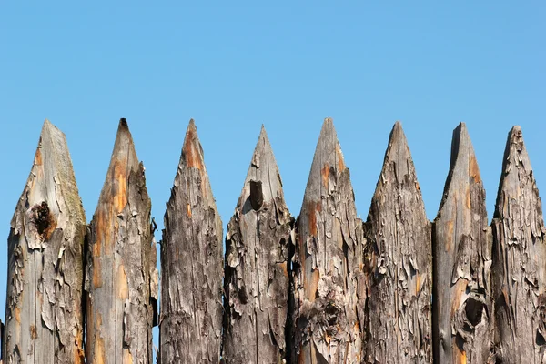 Stockade wooden fence on blue sky background