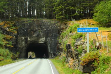 Kvaloyna, Norveç - 16 Haziran 2018: Norveç 'in Rogaland eyaleti Kvaloyna ilçesi yakınlarındaki Aksland Tüneli' nin yol tabelasını geçen motosikletçi.