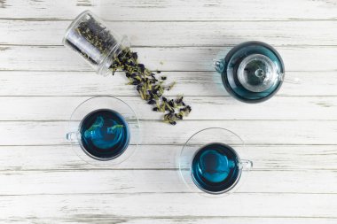 Cam bardaklar ve bir çaydanlık Kelebek bezelye çayı. Anchan, beyaz ahşap arka planda klitoria ternatea. Bir buket mavi çiçekle