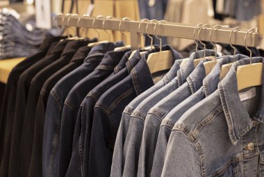 Kadın giysileri - sonbahar kış koleksiyonu. Mağazadaki askıların üzerindeki kot ceketler. Bilinçli tüketim ve geri dönüşüm kavramı.