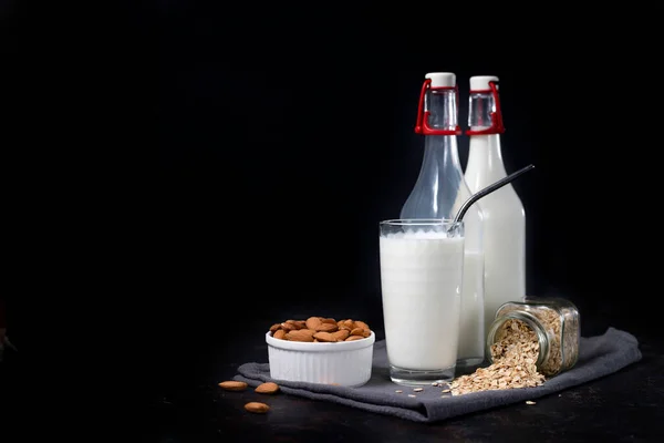 Bir bardak vejetaryen yulaf ezmesi ve koyu arkaplanda badem sütü..