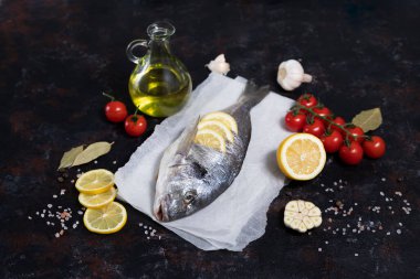 Beyaz kâğıt üzerinde çatal bıçaklı taze dorado balığı. Karanlık bir arka planda. Zeytinyağı, limon, kırmızı biber, sarımsak, tuz ve biberle pişirmek. Akdeniz diyetinin yemeği