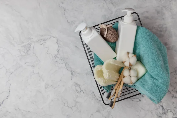 Duş aksesuarları sepetin içinde mermer bir arka planda. İçinde kozmetik, lif, diş fırçası ve havlu şişeleri var. DIY Eko Kozmetik. Kavram sıfır atık, sürdürülebilir. kopyalama alanı. düz yat