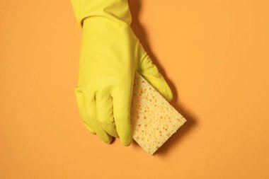 Lastik eldivendeki bir el temizleme süngeri tutar. Sarı renklerde monokrom fotoğrafçılık.