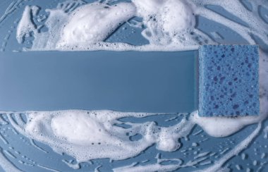 Sabunla temizlik süngeri. Mavi arkaplanda köpük köpüklü doku. kopyalama alanı. Süngerle temizlik..